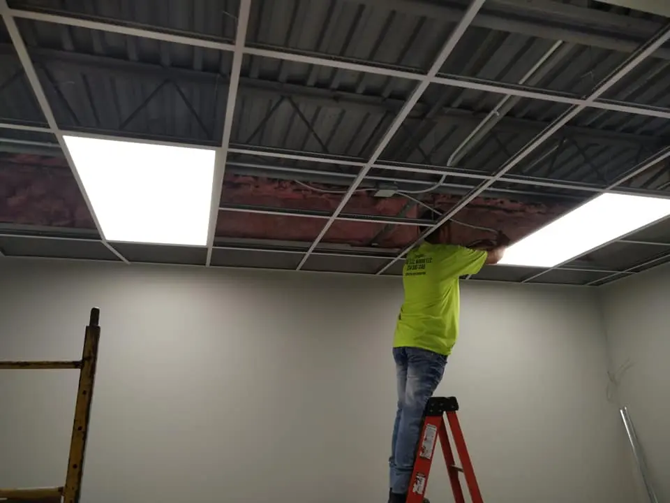 Electrician completing commercial drop-ceiling LED lighting
