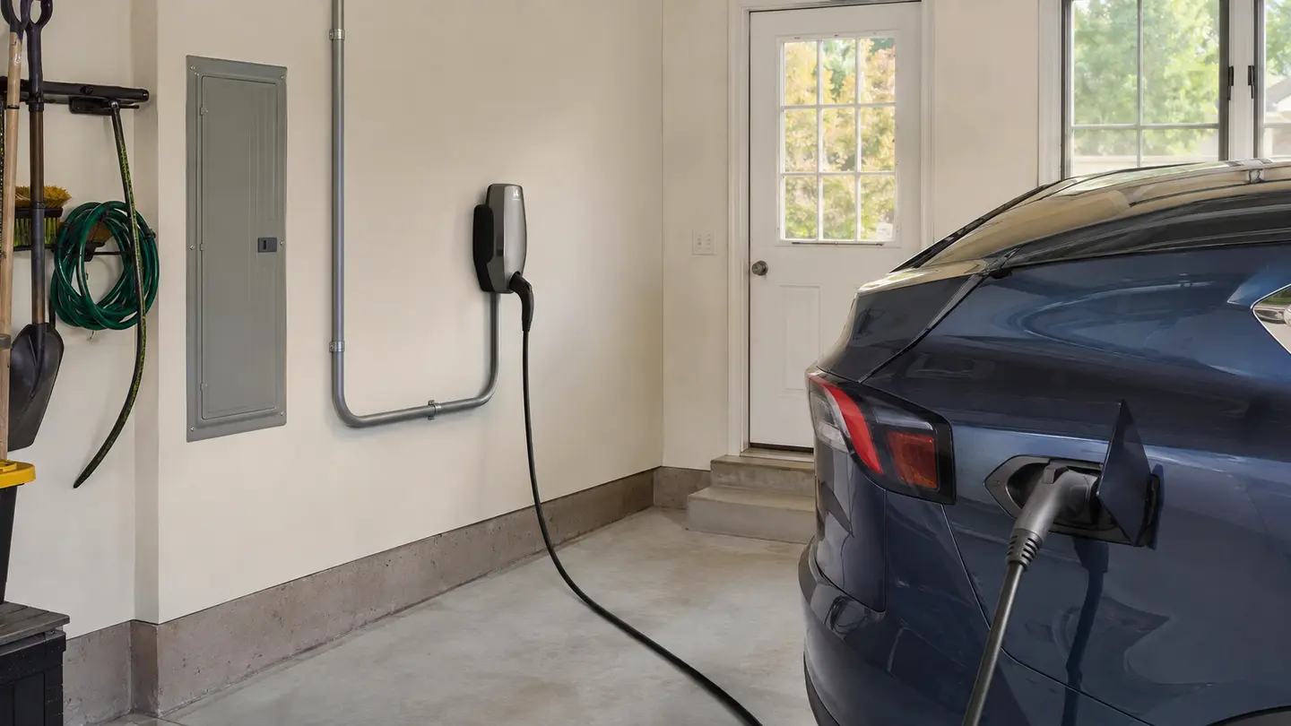 Electric vehicle connected to a wall-mounted Level 2 charger in a residential garage
